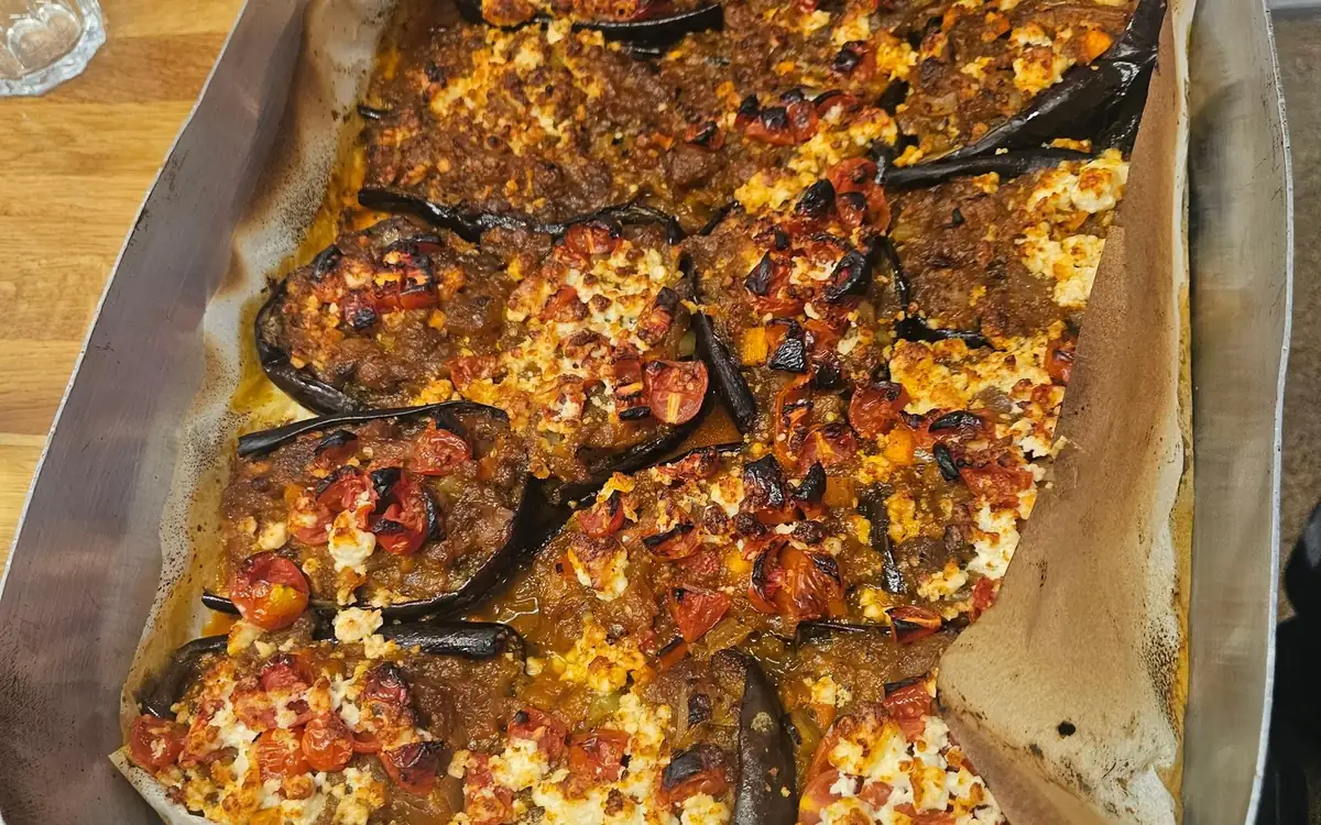Roasted aubergines baked with tomato and crumbled feta in a lined oven tray