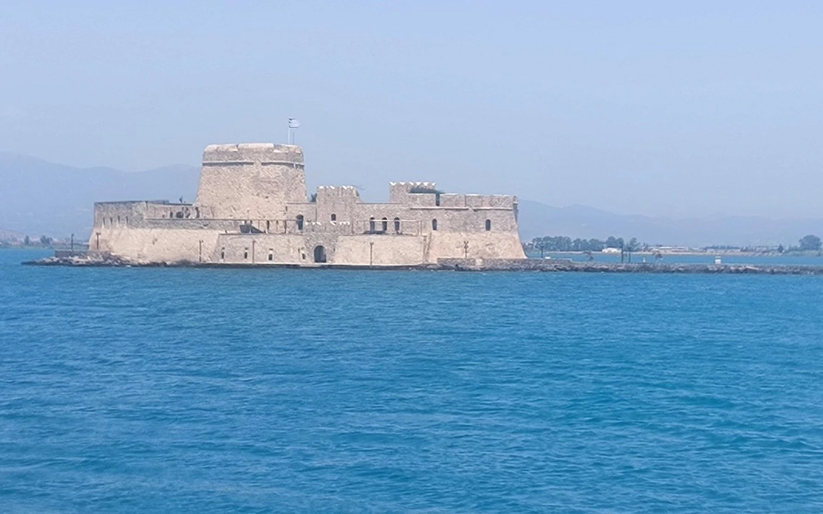 Die Steinfestung Bourtzi auf ihrer Insel in der Bucht vor Nafplio, eine griechische Flagge auf dem Turm