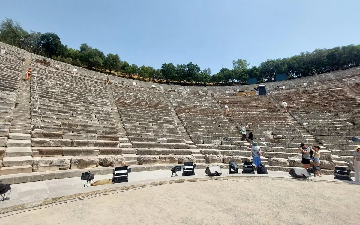 Steinerne Sitzreihen des antiken Theaters von Epidaurus, die sich in weitem Bogen über dem runden Bühnenboden erheben